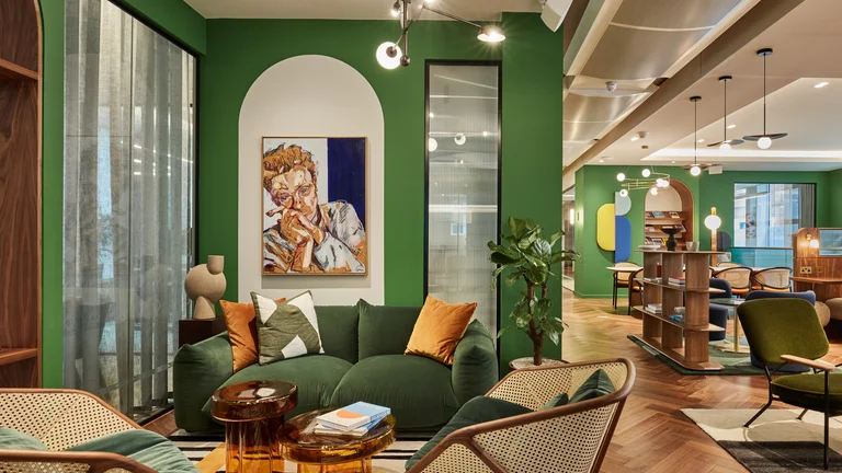 The inside of an office with a green sofa, artwork and green walls