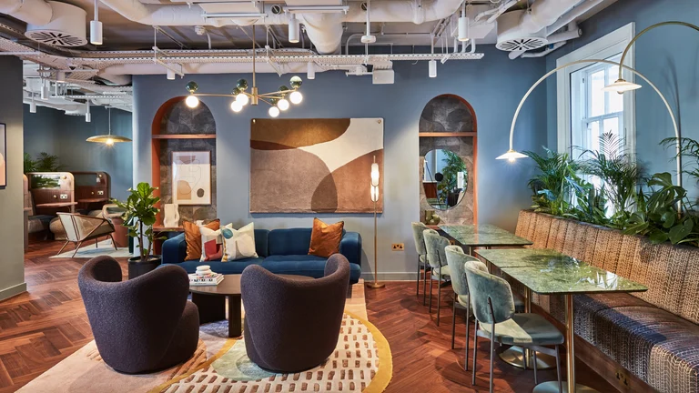 Inside of an office with blue sofas and chairs, artwork on the walls