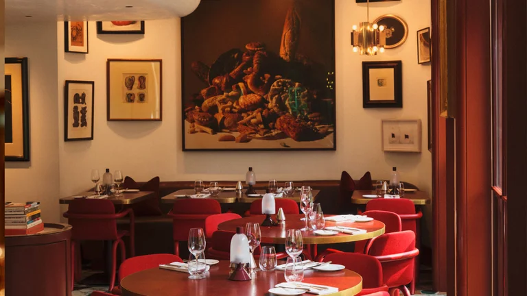 The inside of Mount St. Restaurant with artwork in the background and red tables and chairs