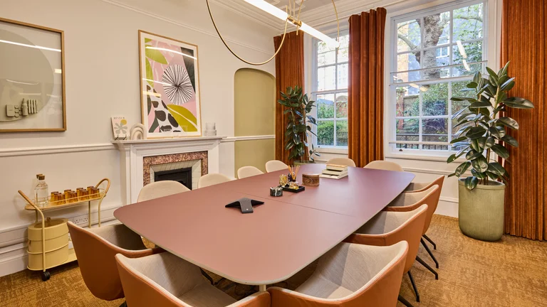 A meeting room with a fireplace, long table and chairs, and artwork