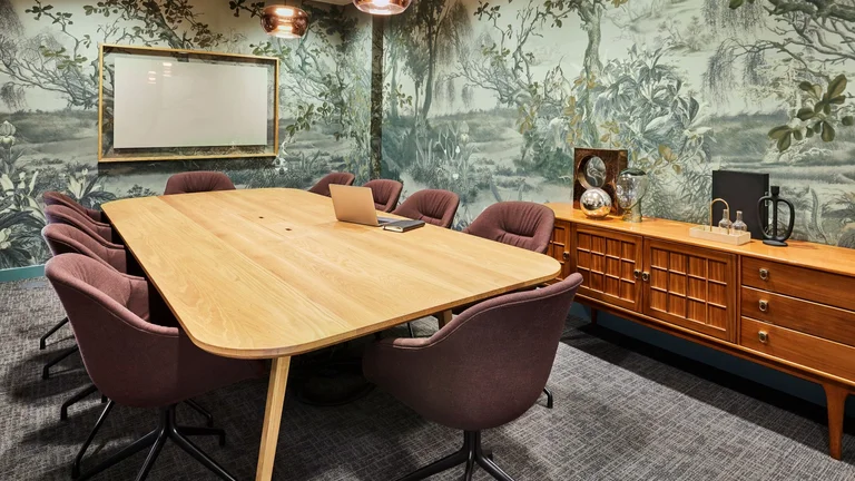 A meeting room with pink chairs around the table 