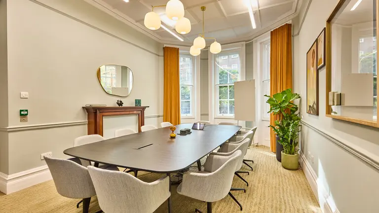 Inside of the meeting room with a large table with chairs around it and a big window in the background