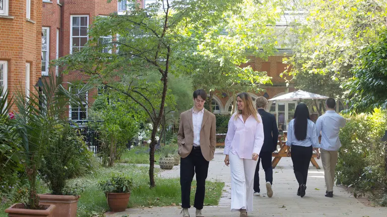 A man and a woman walking through a leafy garden
