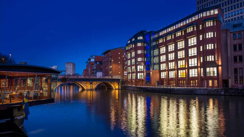A river with a bridge with a large building at night