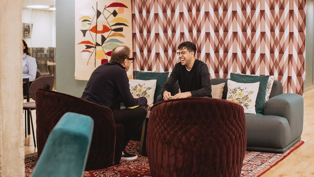 Two men talking on a sofa and an armchair