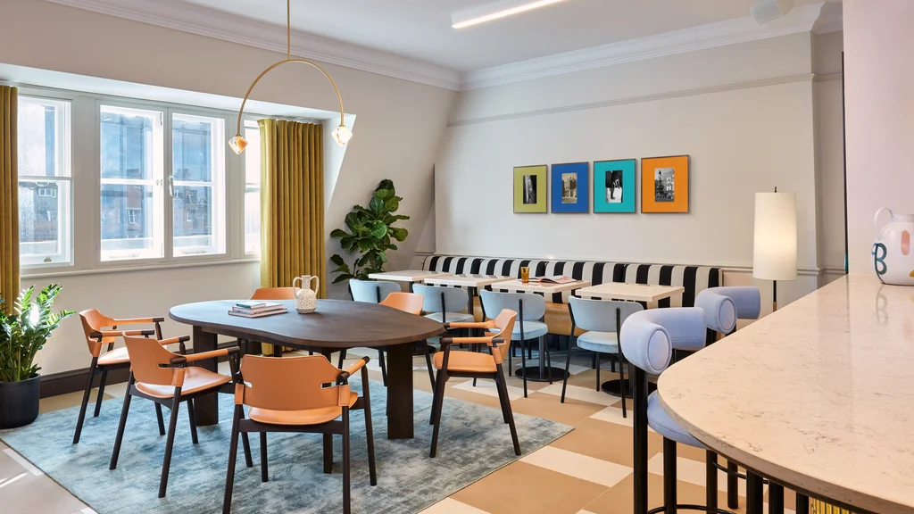 Social area with large central table and six chairs, four additional tables with banquette seating, and a bar area with bar stools.