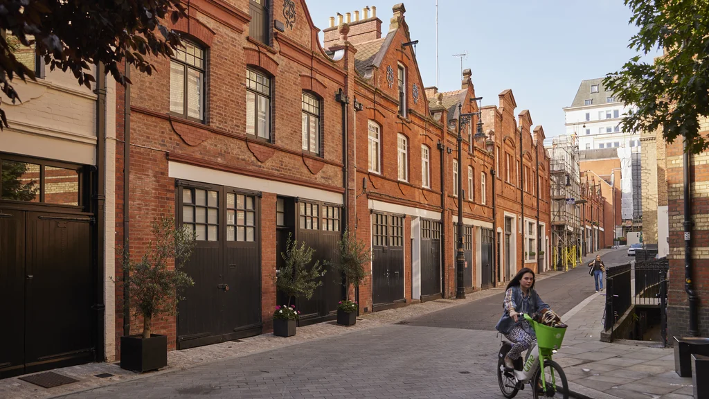 A woman cycling past a row of houses with garages on the ground floor
