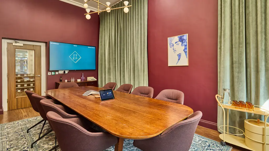 A long table with chairs around it facing a screen