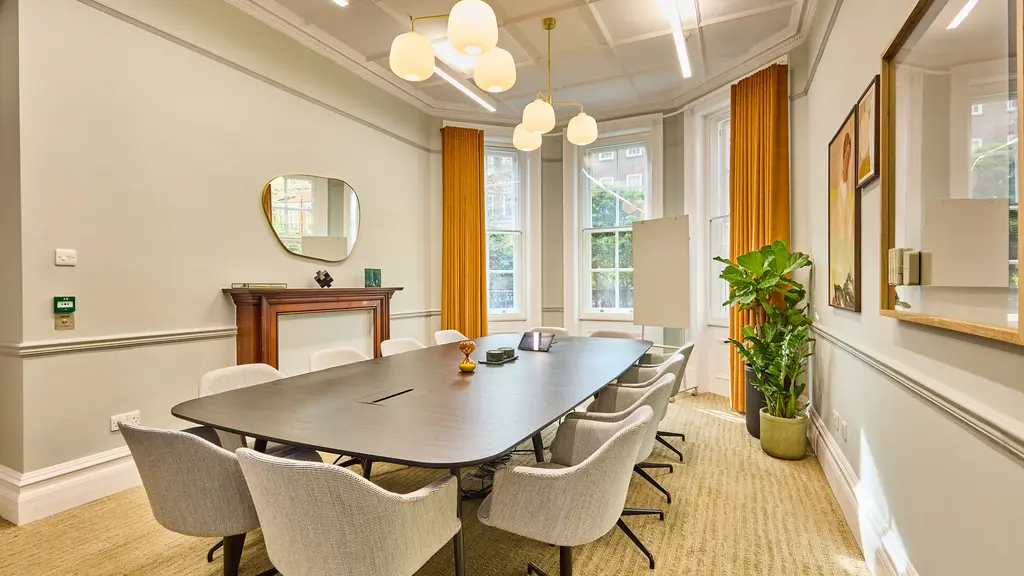 Inside of the meeting room with a large table with chairs around it and a big window in the background