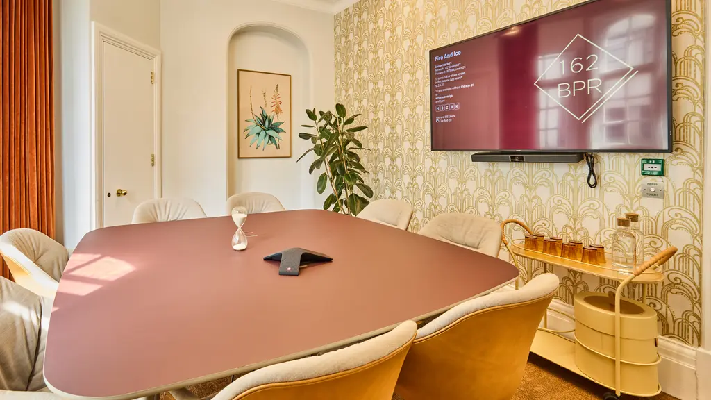A meeting room with table, chairs and a TV screen