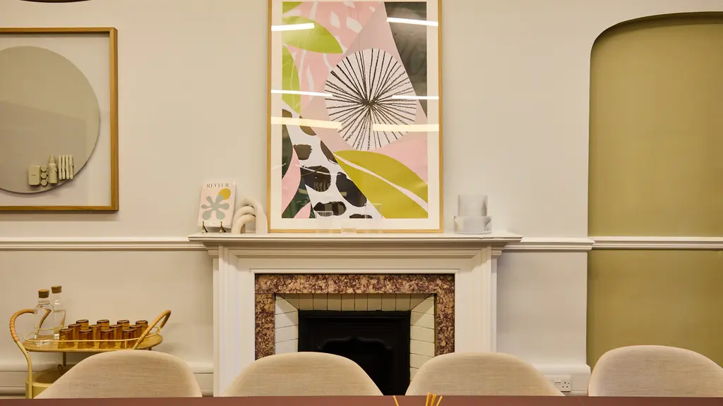 A pink table with a painting on a fireplace in the background