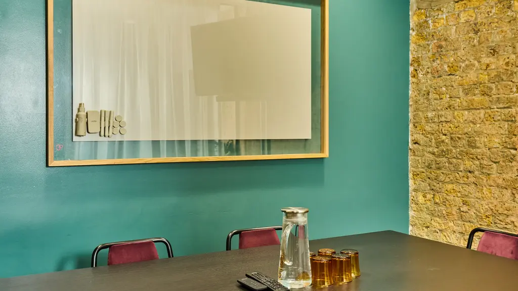 A meeting room with a table, chairs and a whiteboard 