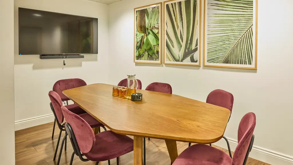 A meeting room with a table, chairs and artwork on the walls