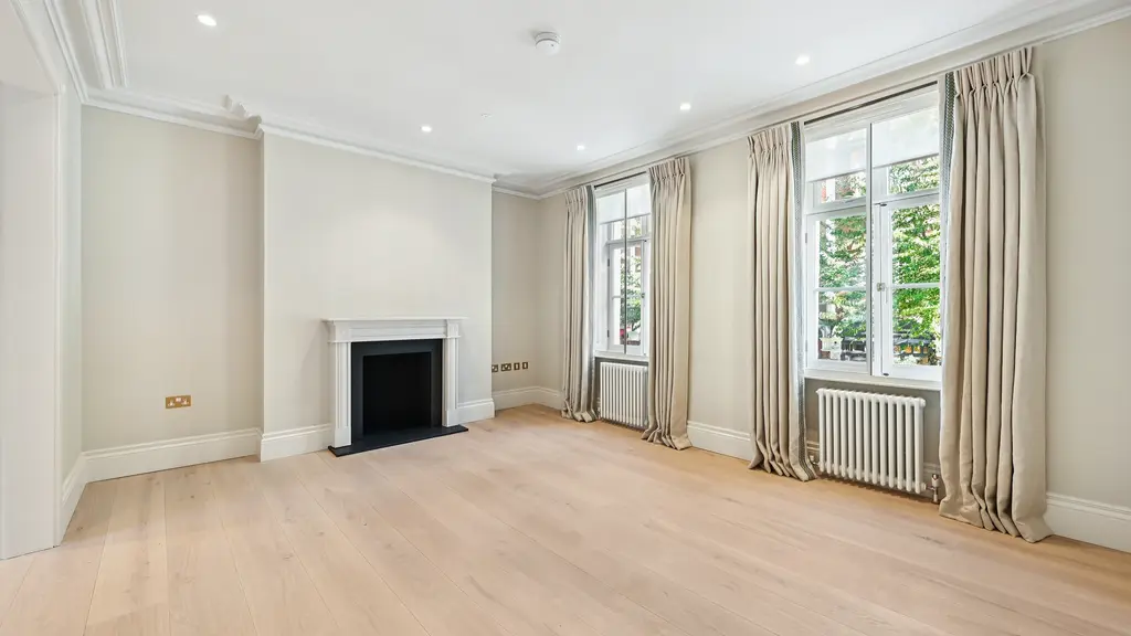 An empty room with a fireplace and two windows