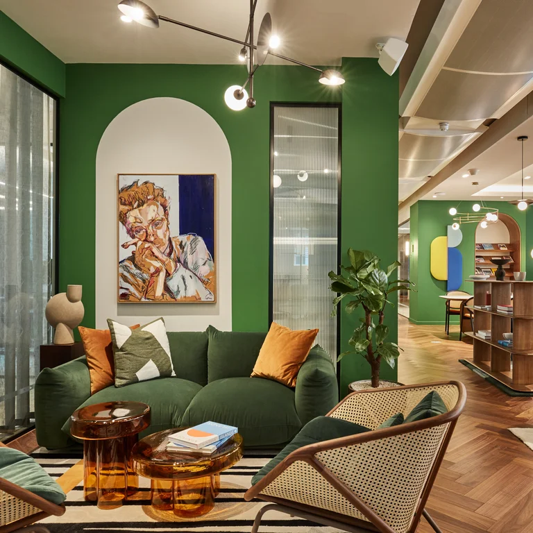 The inside of an office with a green sofa, artwork and green walls