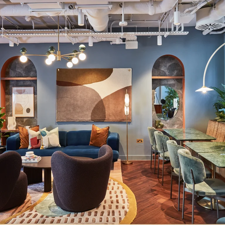 Inside of an office with blue sofas and chairs, artwork on the walls