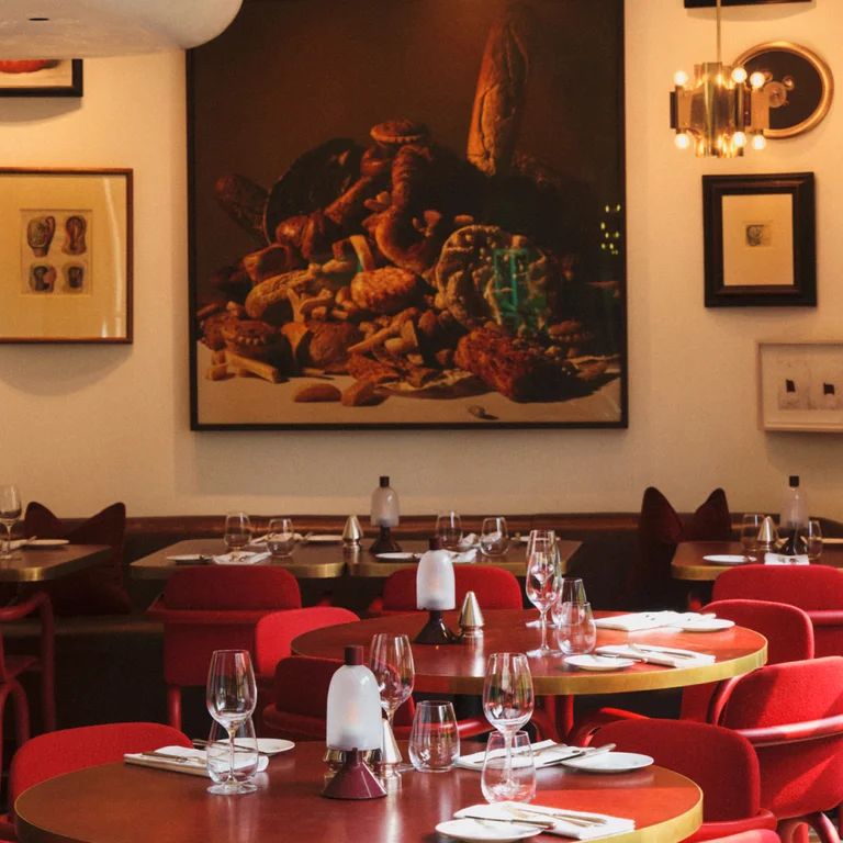The inside of Mount St. Restaurant with artwork in the background and red tables and chairs