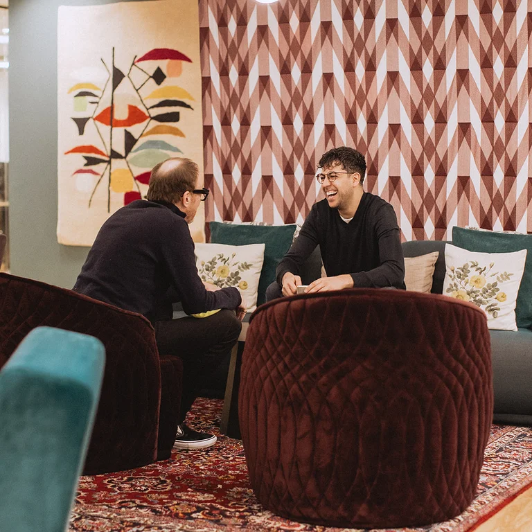 Two men talking on a sofa and an armchair