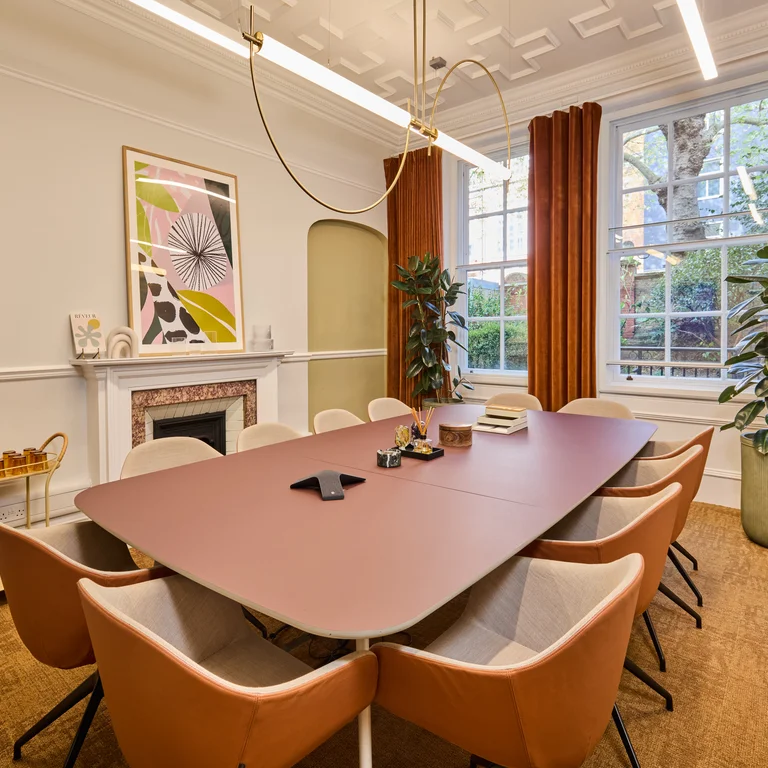 A meeting room with a fireplace, long table and chairs, and artwork